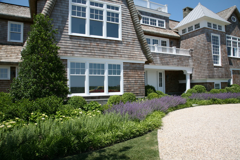 Photo of a large beach style two-storey brown house exterior in New York with wood siding, a gambrel roof and a shingle roof.