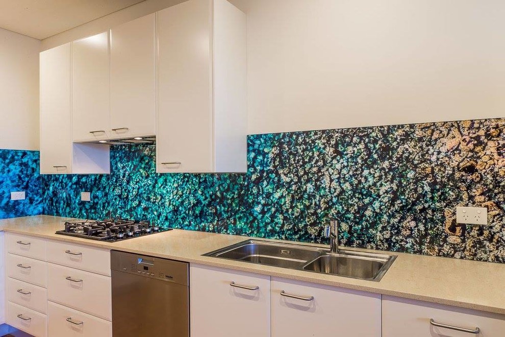This is an example of a tropical kitchen in Sydney with blue splashback and glass sheet splashback.