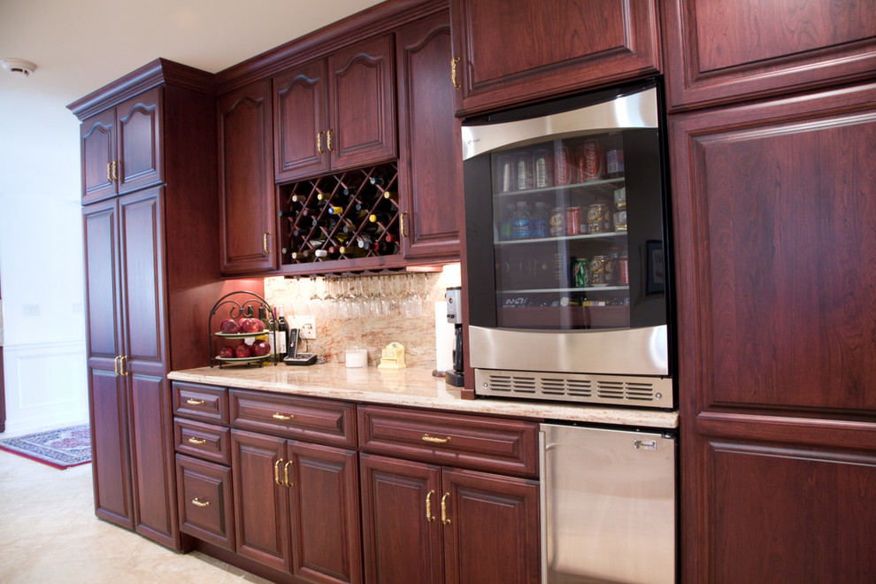 Photo of a mid-sized traditional l-shaped eat-in kitchen in Philadelphia with an undermount sink, raised-panel cabinets, dark wood cabinets, granite benchtops, beige splashback, stone slab splashback, stainless steel appliances, porcelain floors and with island.