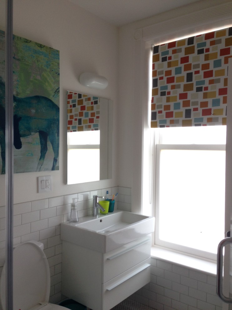 Mid-sized eclectic kids bathroom in New York with a wall-mount sink, flat-panel cabinets, white cabinets, an alcove shower, a two-piece toilet, white tile, subway tile and white walls.