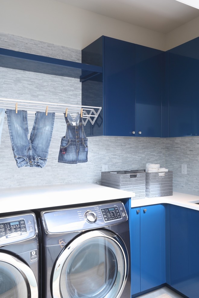 Mid-sized contemporary l-shaped dedicated laundry room in Vancouver with flat-panel cabinets, blue cabinets, a side-by-side washer and dryer, an undermount sink, quartz benchtops, white walls, slate floors and white benchtop.