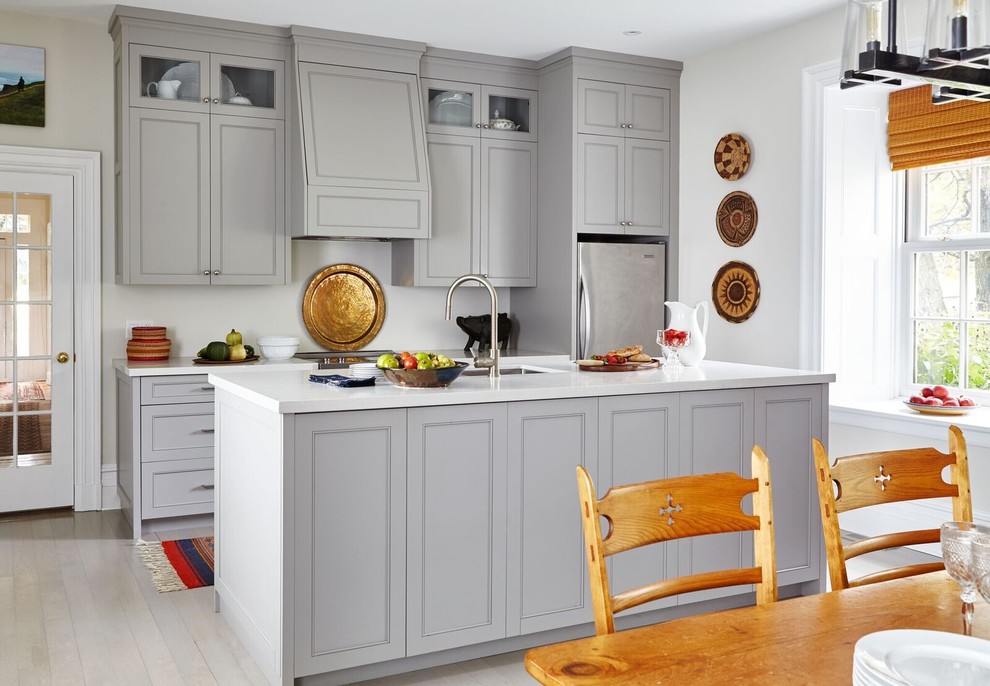 Example of a small transitional galley light wood floor eat-in kitchen design with recessed-panel cabinets, gray cabinets, solid surface countertops, stainless steel appliances, an island and an undermount sink