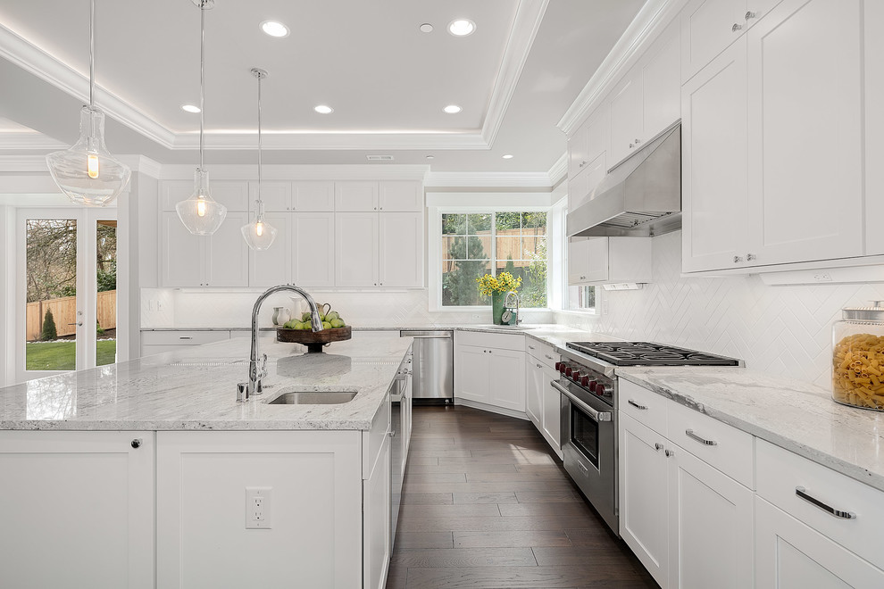This is an example of a large arts and crafts u-shaped eat-in kitchen in Seattle with an undermount sink, recessed-panel cabinets, white cabinets, granite benchtops, white splashback, stainless steel appliances, medium hardwood floors, with island and grey floor.