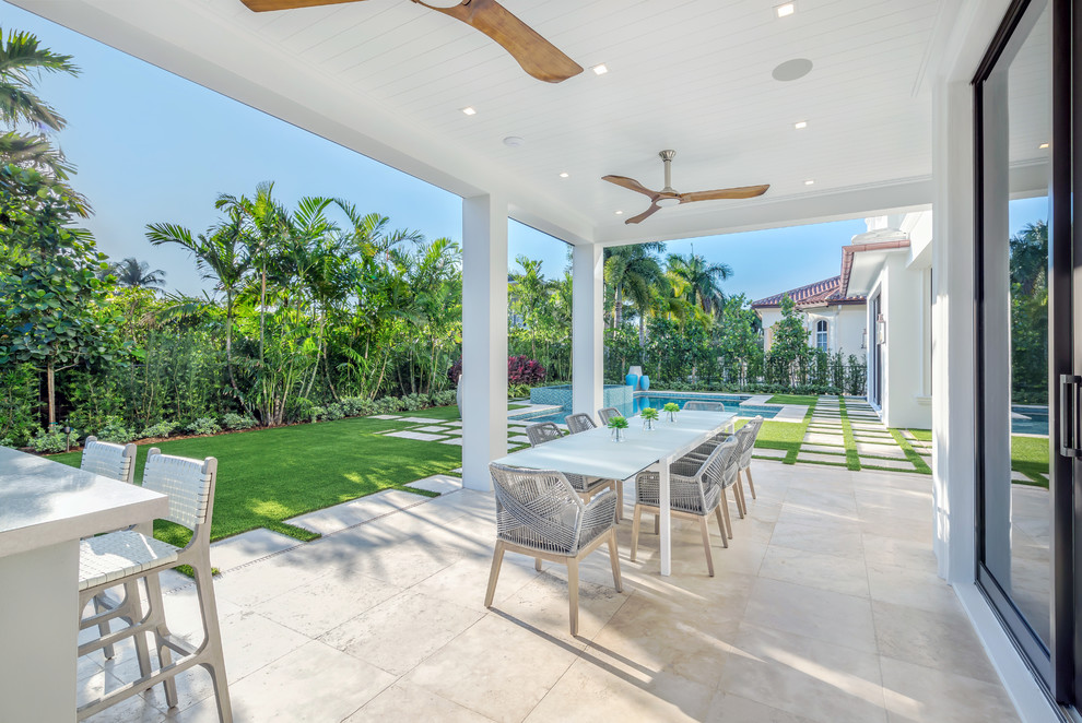 Beach style patio in Miami with tile and a roof extension.