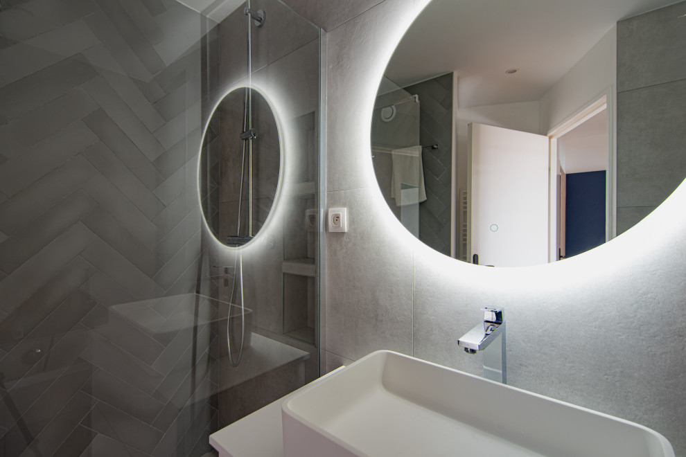 Bild på ett mellanstort funkis badrum med dusch, med vita skåp, ett fristående badkar, våtrum, grå kakel, cementkakel, grå väggar, cementgolv, ett avlångt handfat, grått golv och dusch med gångjärnsdörr