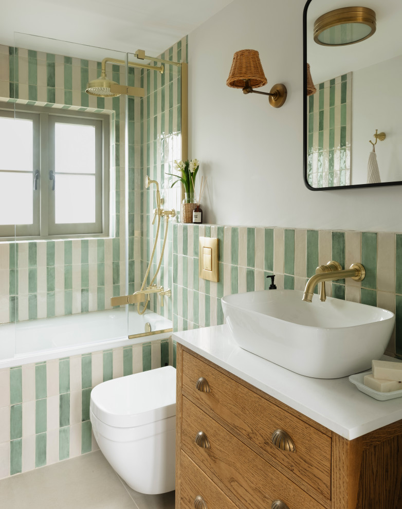 Inspiration for a small eclectic bathroom in Cornwall with white cabinets, a wall mounted toilet, ceramic tiles, ceramic flooring, feature lighting, a single sink, a built-in bath, a shower/bath combination, green tiles, green walls, quartz worktops, grey floors, a hinged door, white worktops and a freestanding vanity unit.