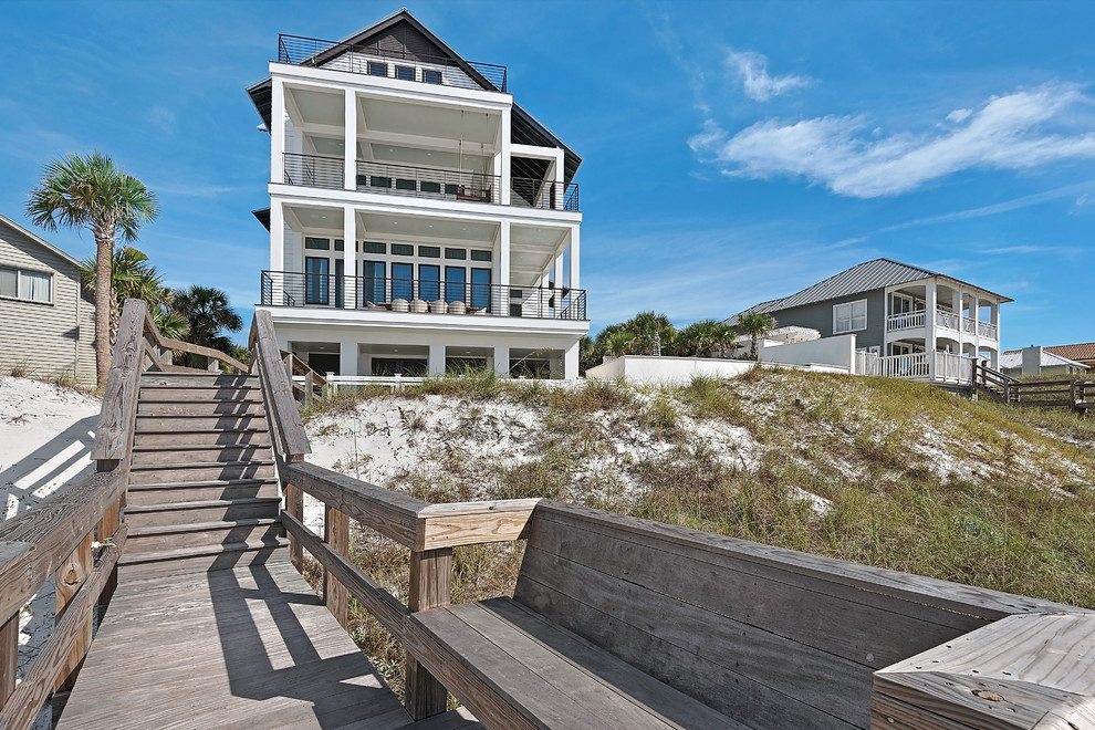 Photo of an expansive beach style three-storey white exterior in Miami with wood siding and a gable roof.