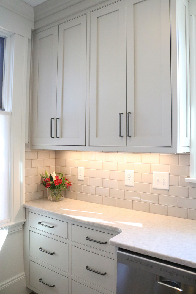 Large transitional galley medium tone wood floor and brown floor enclosed kitchen photo with a farmhouse sink, shaker cabinets, gray cabinets, quartzite countertops, stainless steel appliances, beige backsplash, subway tile backsplash and a peninsula