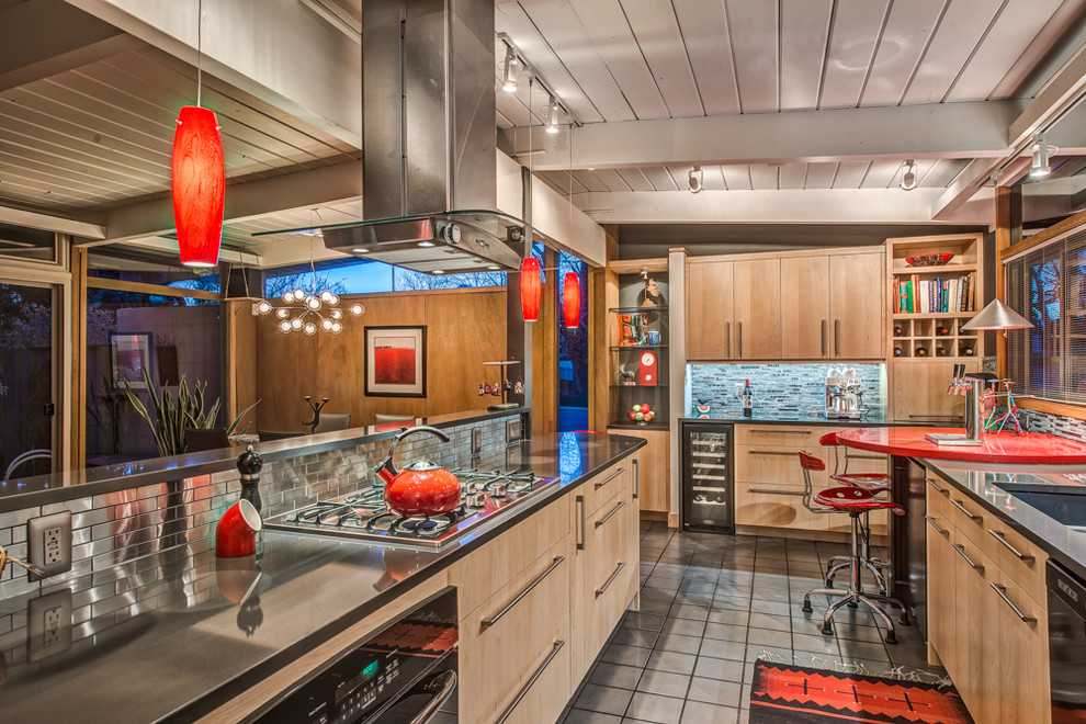 This is an example of a mid-sized midcentury galley open plan kitchen in Denver with an undermount sink, flat-panel cabinets, light wood cabinets, quartz benchtops, metallic splashback, metal splashback, black appliances, porcelain floors and with island.