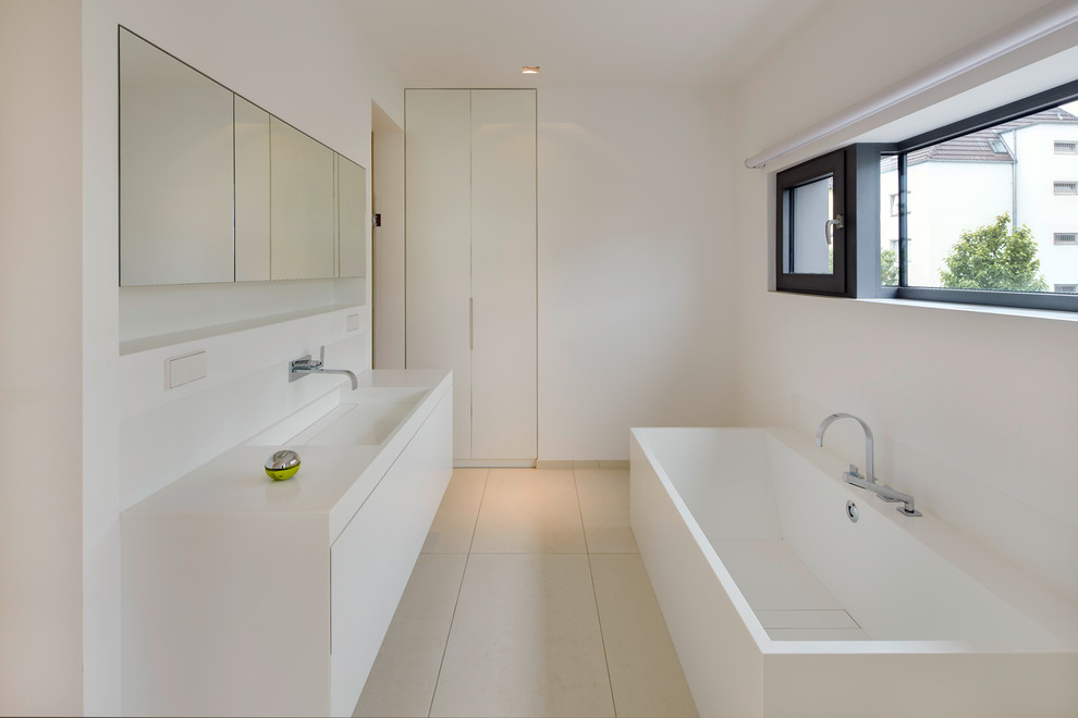 Inspiration for a mid-sized contemporary bathroom in Cologne with flat-panel cabinets, white cabinets, beige tile, stone tile, white walls and limestone floors.