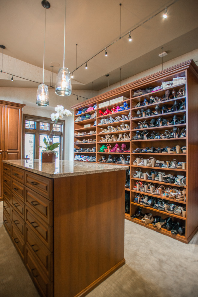 Inspiration for an expansive traditional gender-neutral walk-in wardrobe in Denver with raised-panel cabinets, medium wood cabinets, carpet and beige floor.