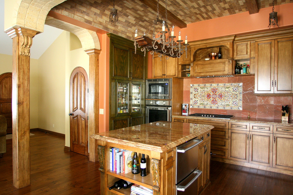 This is an example of a mid-sized mediterranean u-shaped open plan kitchen in Los Angeles with an undermount sink, beaded inset cabinets, medium wood cabinets, granite benchtops, orange splashback, stone tile splashback, stainless steel appliances, medium hardwood floors and with island.