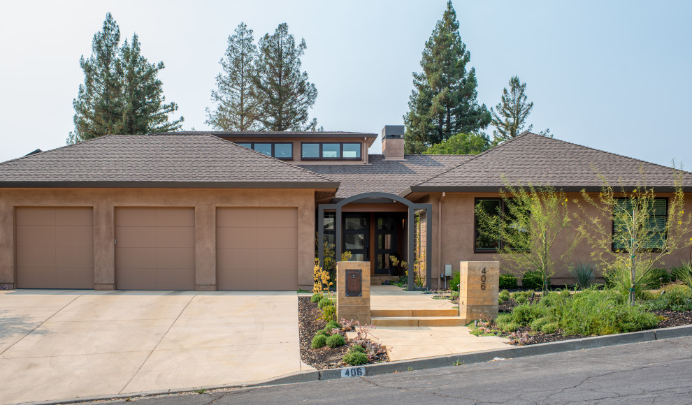 Photo of an expansive country one-storey stucco brown house exterior in San Francisco with a hip roof, a shingle roof and a brown roof.