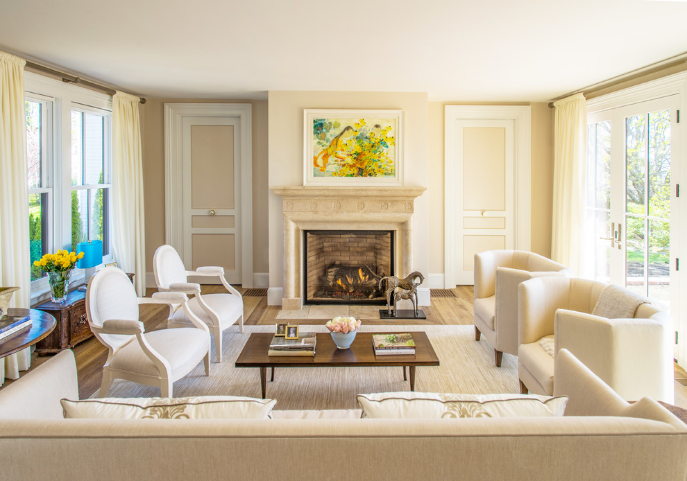 Photo of a large traditional formal living room in Boston with beige walls, a standard fireplace, a stone fireplace surround and beige floor.