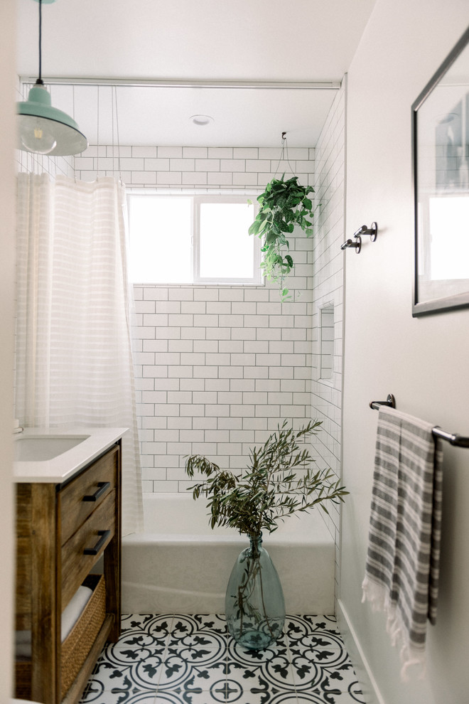 Inspiration for a small country 3/4 bathroom in San Diego with flat-panel cabinets, medium wood cabinets, a corner tub, an alcove shower, a two-piece toilet, white tile, subway tile, white walls, porcelain floors, a console sink, engineered quartz benchtops, black floor, a shower curtain and white benchtops.