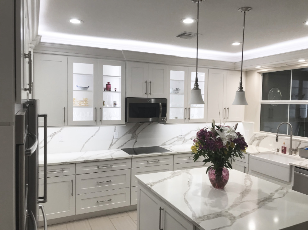 This is an example of a mid-sized transitional u-shaped eat-in kitchen in Other with a farmhouse sink, shaker cabinets, white cabinets, quartz benchtops, multi-coloured splashback, engineered quartz splashback, stainless steel appliances, with island and multi-coloured benchtop.