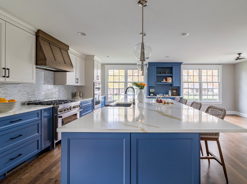 Photo of a medium sized classic kitchen/diner in Chicago with a submerged sink, blue cabinets, engineered stone countertops, glass tiled splashback, stainless steel appliances, medium hardwood flooring and an island.