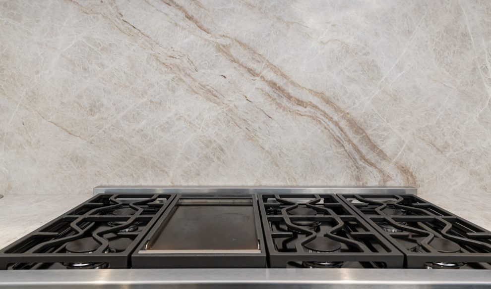 Large transitional medium tone wood floor and brown floor open concept kitchen photo with a double-bowl sink, flat-panel cabinets, white cabinets, quartzite countertops, beige backsplash, stainless steel appliances, an island and beige countertops