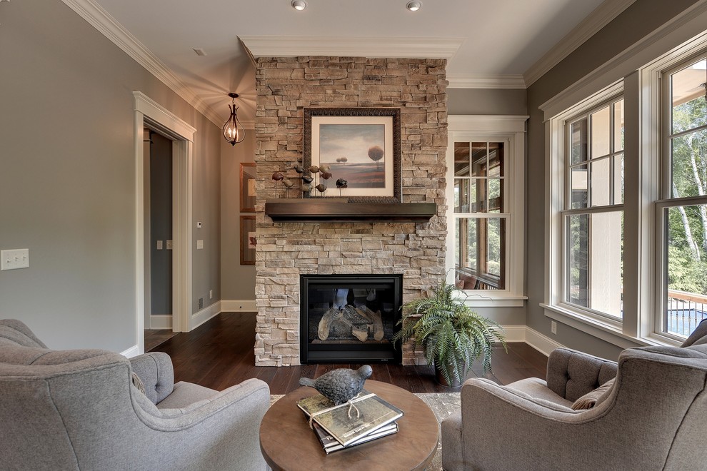 Inspiration for a traditional enclosed living room in Minneapolis with beige walls, dark hardwood floors, a standard fireplace, a stone fireplace surround and brown floor.
