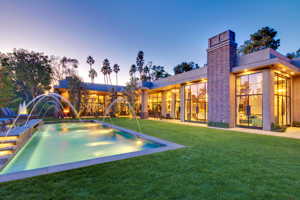 This is an example of a transitional rectangular pool in Los Angeles with a water feature.