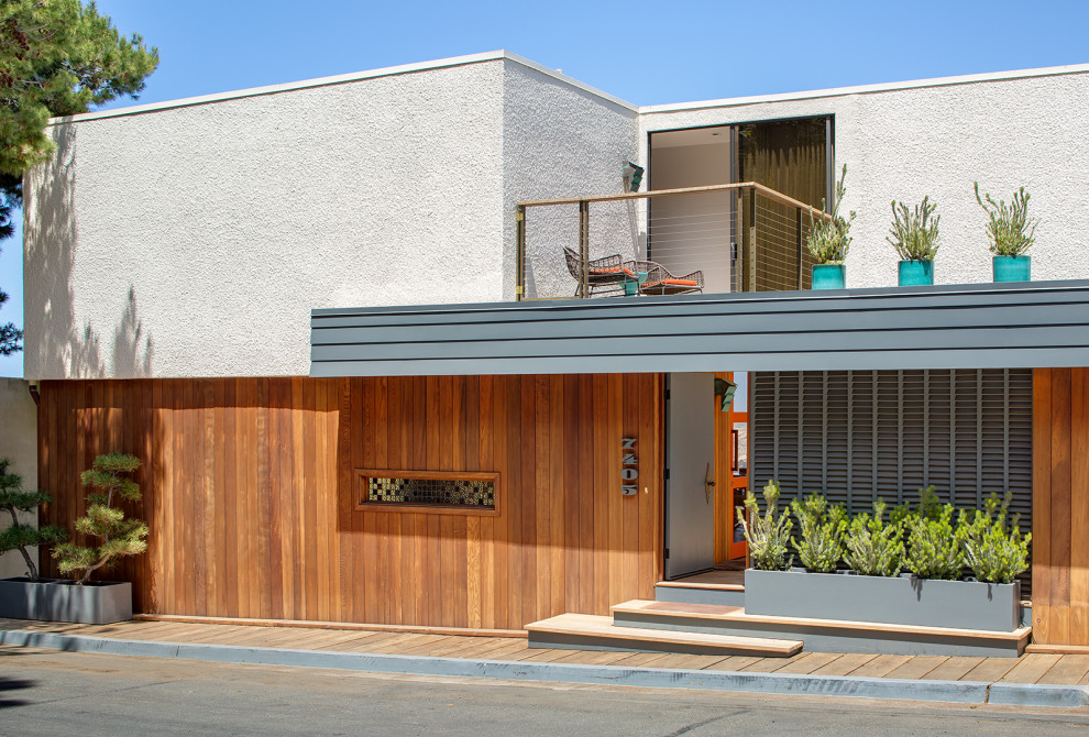 Mittelgroßes, Zweistöckiges Retro Einfamilienhaus mit Mix-Fassade, brauner Fassadenfarbe, Flachdach, weißem Dach und Verschalung in San Diego