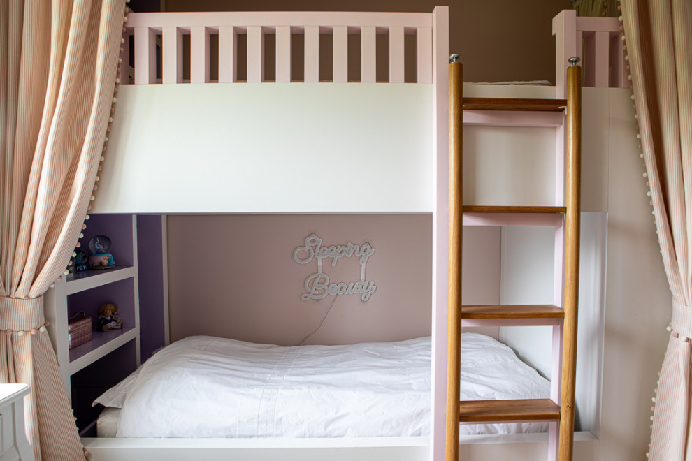 Mid-sized contemporary kids' bedroom in London with pink walls, light hardwood floors, grey floor and wallpaper for kids 4-10 years old and girls.