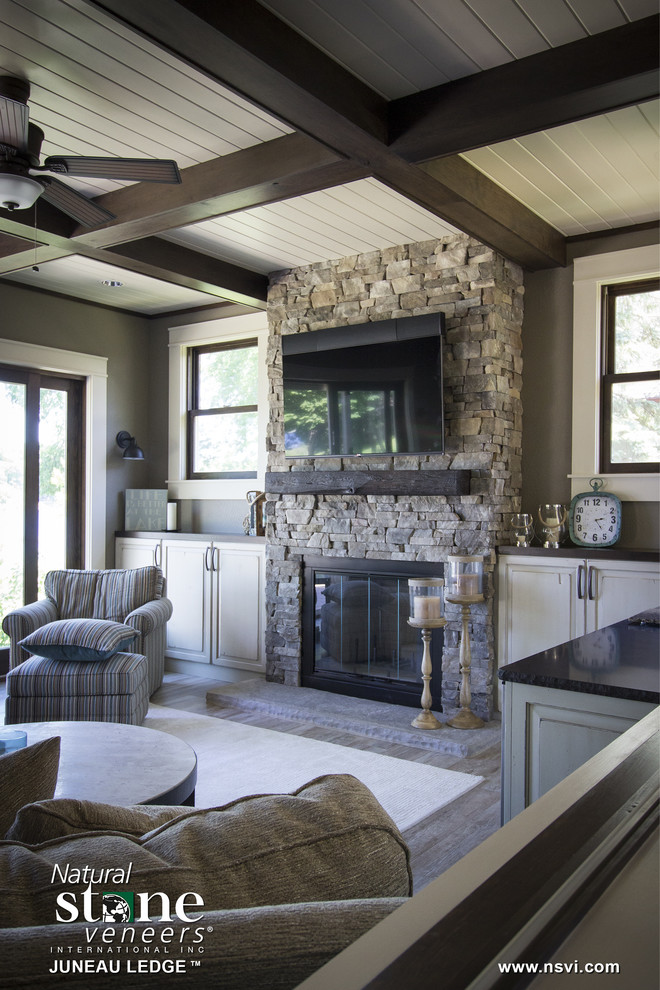 This is an example of a transitional sunroom in Milwaukee with a standard fireplace and a stone fireplace surround.