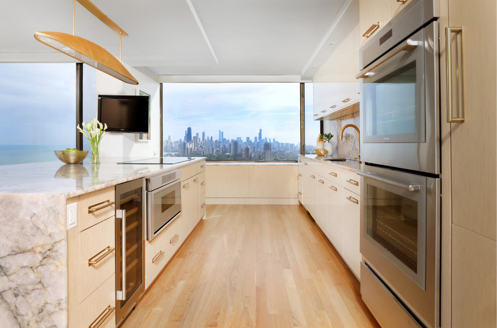 This is an example of a mid-sized modern galley eat-in kitchen in Chicago with flat-panel cabinets, white cabinets, quartzite benchtops, with island, a single-bowl sink, yellow splashback, stone slab splashback, stainless steel appliances, light hardwood floors, beige floor and white benchtop.