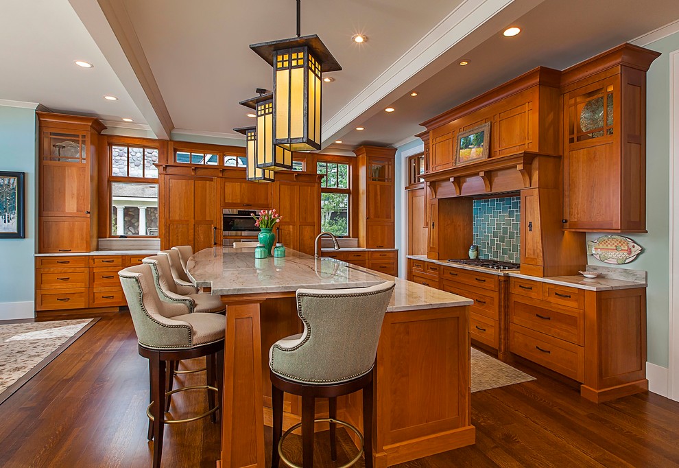 This is an example of a large arts and crafts l-shaped eat-in kitchen in Grand Rapids with recessed-panel cabinets, medium wood cabinets, quartz benchtops, stainless steel appliances, dark hardwood floors, with island and brown floor.