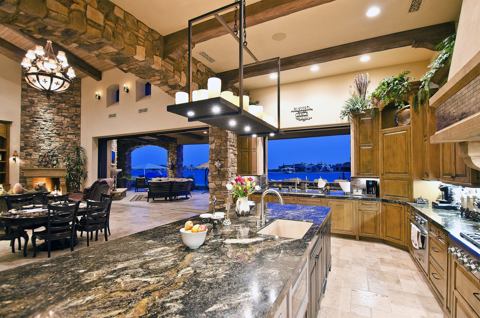 Large mediterranean u-shaped open plan kitchen in Los Angeles with a single-bowl sink, raised-panel cabinets, medium wood cabinets, granite benchtops, brown splashback, ceramic splashback, stainless steel appliances, travertine floors and with island.