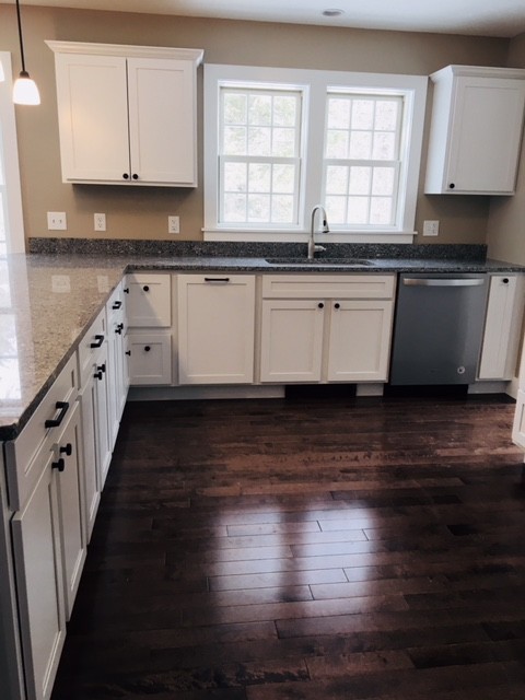 Photo of a country u-shaped open plan kitchen in Boston with an undermount sink, shaker cabinets, white cabinets, granite benchtops, stainless steel appliances, dark hardwood floors, a peninsula and brown floor.