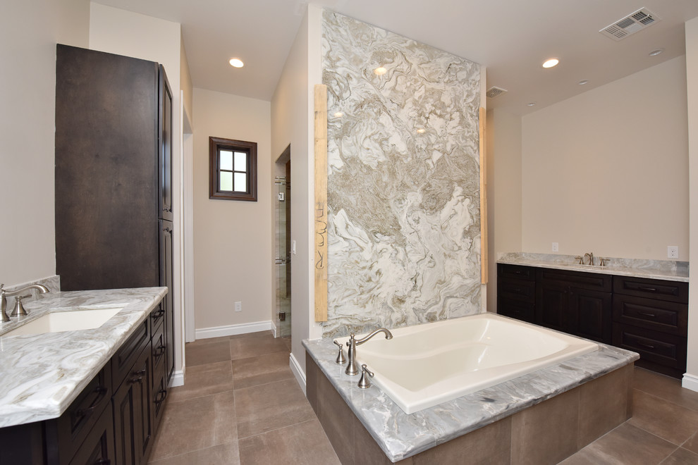 Inspiration for a large contemporary master bathroom in Phoenix with raised-panel cabinets, dark wood cabinets, a drop-in tub, a double shower, gray tile, marble, beige walls, porcelain floors, an undermount sink, marble benchtops, grey floor and a hinged shower door.