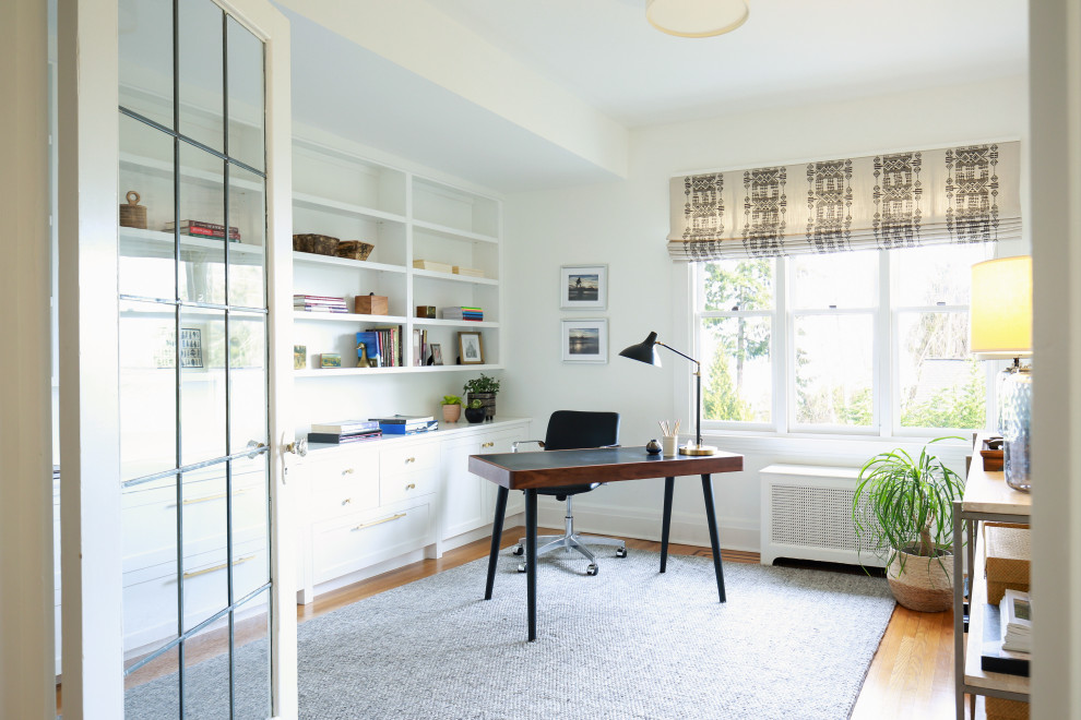 Mittelgroßes Stilmix Arbeitszimmer ohne Kamin mit Arbeitsplatz, weißer Wandfarbe, hellem Holzboden, freistehendem Schreibtisch und braunem Boden in Seattle