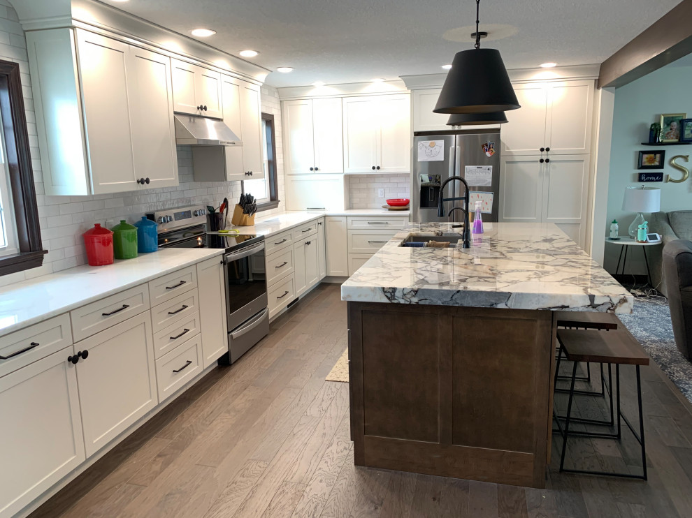 Open concept kitchen - large transitional l-shaped open concept kitchen idea with an undermount sink, shaker cabinets, white cabinets, stainless steel appliances and an island