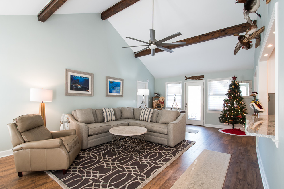 Design ideas for a mid-sized country open concept living room in Charleston with blue walls, medium hardwood floors, a standard fireplace, a brick fireplace surround and a wall-mounted tv.