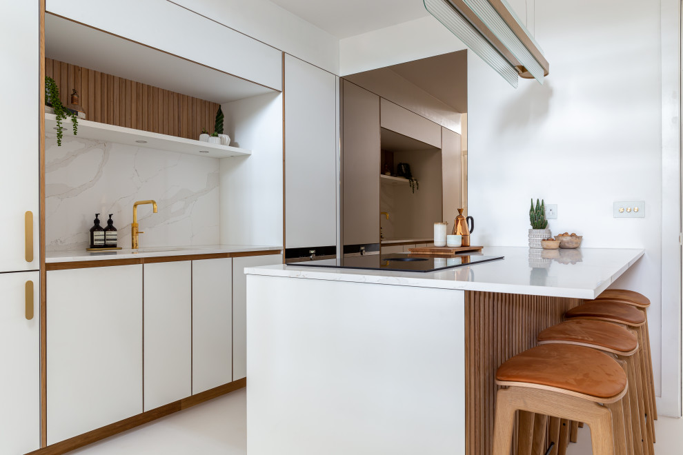 Inspiration pour une petite cuisine linéaire nordique avec un placard à porte plane, des portes de placard blanches, un plan de travail en surface solide, une crédence blanche, un électroménager blanc et un plan de travail blanc.
