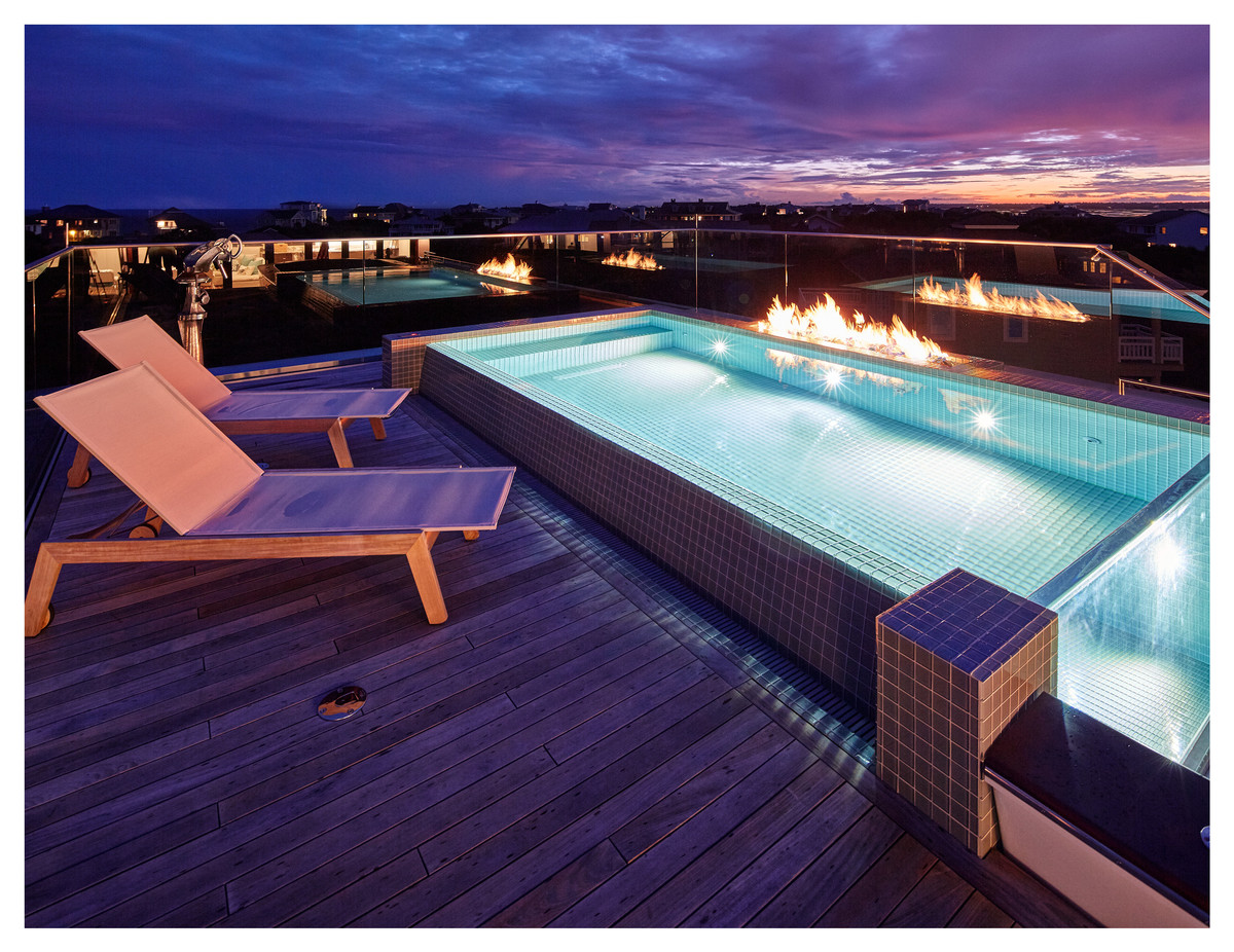 Mid-sized contemporary rooftop rectangular infinity pool in Other with a pool house and decking.