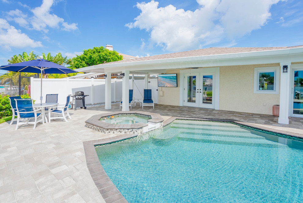 Imagen de casa de la piscina y piscina alargada grande redondeada en patio trasero con adoquines de ladrillo