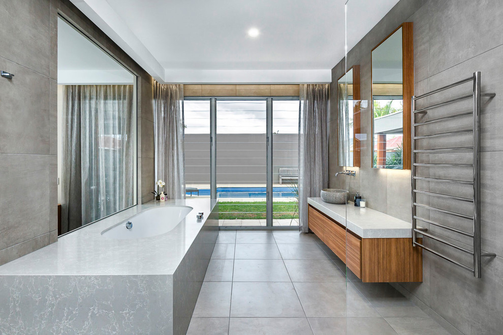 Inspiration for a contemporary master bathroom in Adelaide with flat-panel cabinets, medium wood cabinets, an undermount tub, gray tile, cement tile, grey walls, cement tiles, a vessel sink, grey floor and grey benchtops.