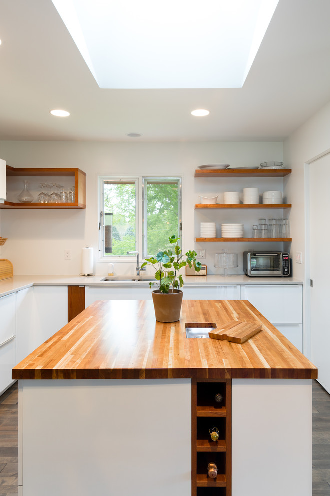 This is an example of a mid-sized midcentury l-shaped open plan kitchen in Omaha with a double-bowl sink, flat-panel cabinets, white cabinets, laminate benchtops, white splashback, stainless steel appliances, dark hardwood floors, multiple islands and black floor.