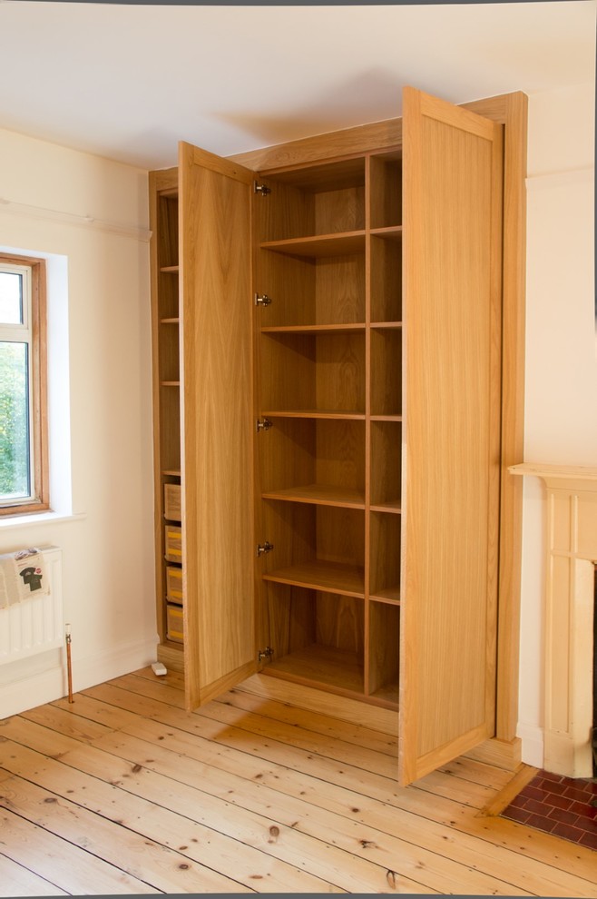 Inspiration for a contemporary gender-neutral built-in wardrobe in Oxfordshire with recessed-panel cabinets and light wood cabinets.