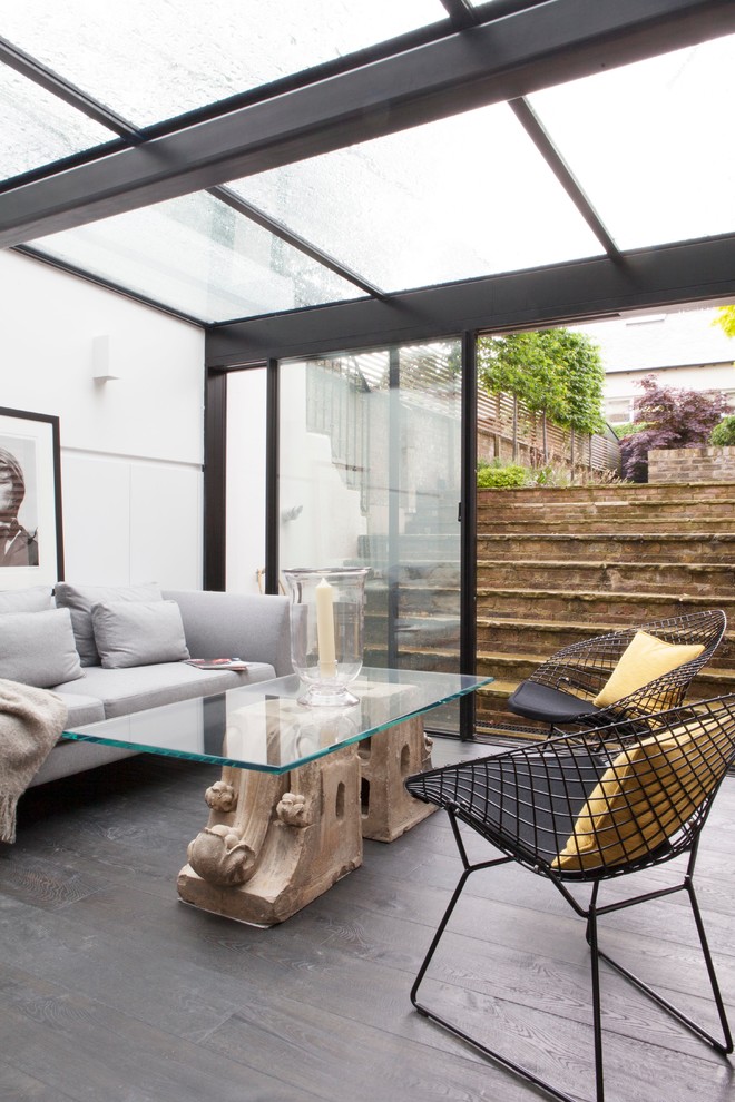 Contemporary sunroom in London with dark hardwood floors, a glass ceiling and grey floor.