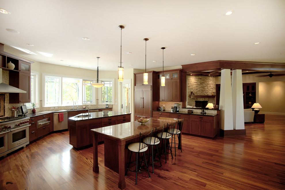 Design ideas for a large arts and crafts u-shaped open plan kitchen in Chicago with an undermount sink, shaker cabinets, medium wood cabinets, granite benchtops, stainless steel appliances, medium hardwood floors and multiple islands.