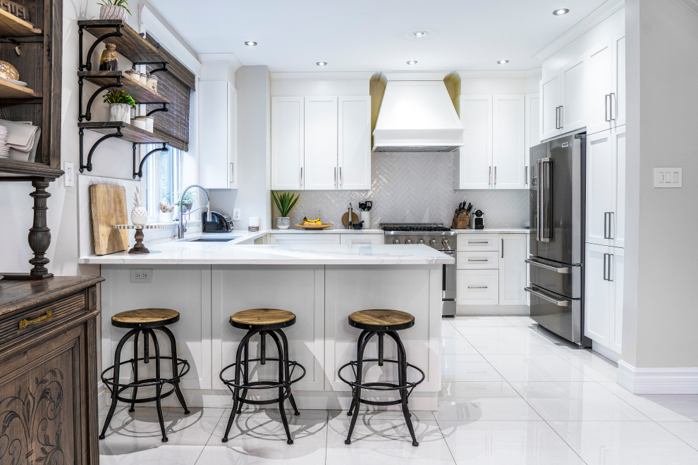 Mid-sized transitional u-shaped kitchen pantry in Montreal with an undermount sink, shaker cabinets, white cabinets, quartz benchtops, white splashback, subway tile splashback, stainless steel appliances, porcelain floors, with island, beige floor and white benchtop.