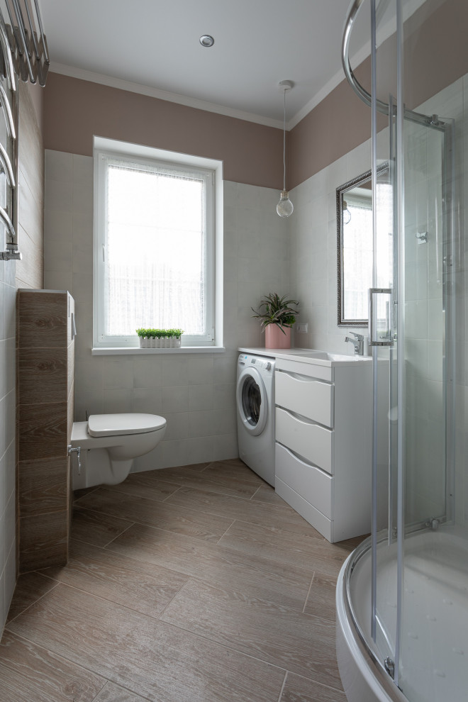 This is an example of a contemporary bathroom in Other with flat-panel cabinets, white cabinets, a corner shower, a wall-mount toilet, white tile, wood-look tile, an integrated sink, brown floor, white benchtops, a laundry, a single vanity and a built-in vanity.