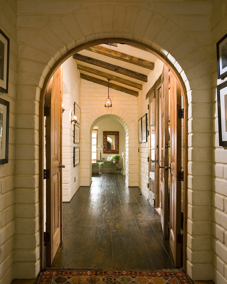 Inspiration for a mid-sized hallway in Santa Barbara with dark hardwood floors, white walls and brown floor.
