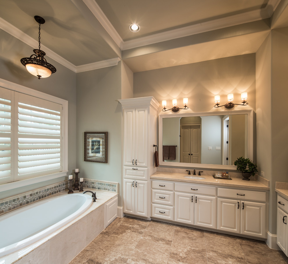 Mid-sized traditional master bathroom in Houston with an undermount sink, raised-panel cabinets, white cabinets, marble benchtops, a drop-in tub, an alcove shower, a one-piece toilet, beige tile, ceramic tile, blue walls and porcelain floors.