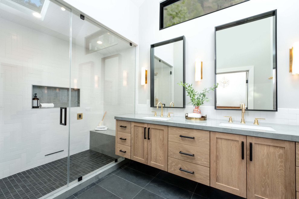 This is an example of a large transitional wet room bathroom in San Francisco with shaker cabinets, medium wood cabinets, a one-piece toilet, white tile, ceramic tile, white walls, slate floors, an undermount sink, engineered quartz benchtops, black floor, a hinged shower door, grey benchtops, a shower seat, a double vanity and a floating vanity.