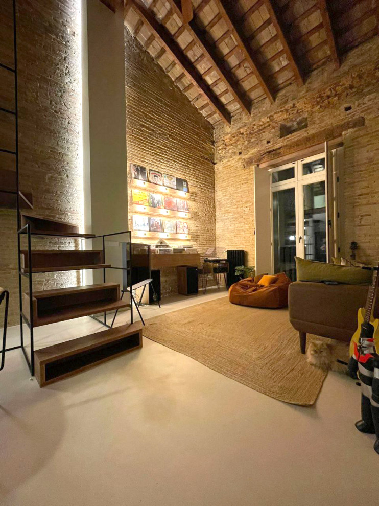 Photo of a small industrial mezzanine living room in Valencia with a music area, beige walls, concrete flooring, grey floors, exposed beams and brick walls.