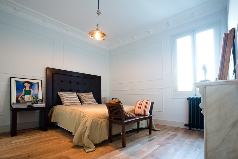 Contemporary bedroom in Paris with white walls, light hardwood floors and no fireplace.